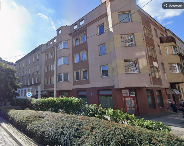 Budynek Ośrodka Wsparcia i Testów we Wrocławiu. Trzypiętrowy budynek o beżowo-brązowej elewacji z narożnym wejściem