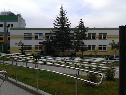 Jednopiętrowy budynek z biało-pomarańczowa elewacją wraz z podjazdem dla wózków